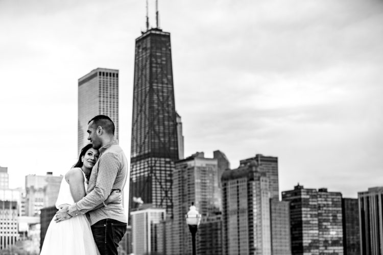 Couple hugging with Chicago skyline background during their destination engagement photo session